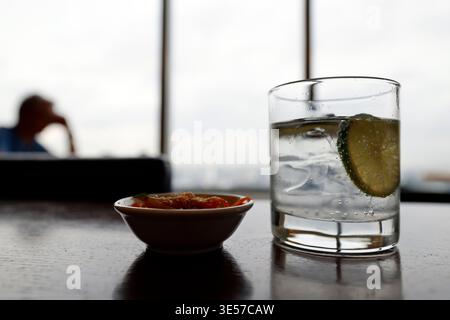 Erfrischende Limonade mit Limettenscheibe neben einer scharfen Dip-Sauce, Dachterrasse. Vietnam. Stockfoto