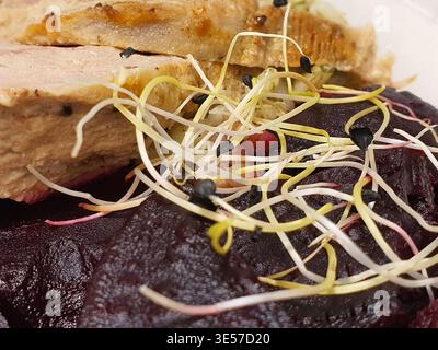Makrofoto aus der Nähe eines Gourmet-Tellers mit geschnittenem geröstetem Fleisch mit knuspriger goldbrauner Haut, wahrscheinlich Ente oder Schweinefleisch, auf einem Stockfoto