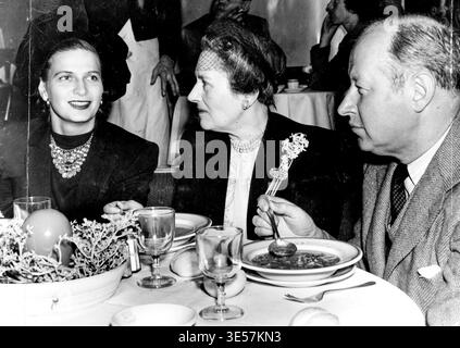 Quadratische Mahlzeit mit Besatz für Eugene Goossens, seine Frau (links), und Melbourne-Freundin, Mrs. St. John Scott-Scott, letzte Woche im Prince's, Nacht vor dem großen Konzert ... nur leichtes Essen ist möglich, bevor er dirigiert ... Mrs. Goossens sucht immer noch nach einem Haus und wartet immer noch darauf, dass der Rest ihrer Koffer auf dem Seeweg ankommt. Mrs. Goossens Hut war aus gesammeltem schwarzem Samt und bildete einen blumigen Rahmen für ihr attraktives Gesicht, das trotz der unaufhörlichen sozialen Anforderungen an sie seit ihrer Ankunft vor fast drei Wochen immer noch seine Frische verloren hat. 30. Juli 1947. Stockfoto