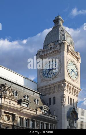 Paris, Frankreich - 7. Mai 2022: Nahaufnahme des Uhrenturms des Bahnhofs Gare de Lyon mit skulpturalen Fassadendetails vor bewölktem Himmel Stockfoto