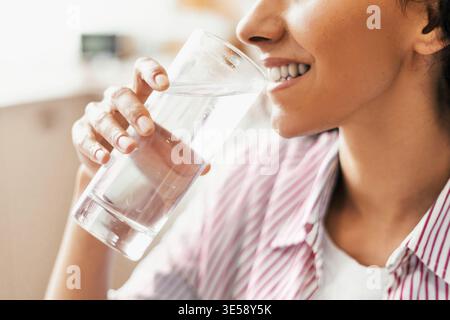 Frau trinkt Wasser während des Tages in einer ungezwungenen Umgebung Stockfoto
