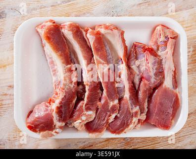Schneiden Sie rohe Schweinerippchen in eine Kunststoffschale Stockfoto