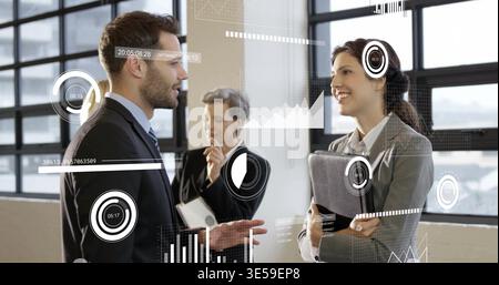 Ein Mann im dunklen Anzug und eine Frau, die ein Tablet in einem hellen Büro mit Fenstern und HUD-Overlays hält Stockfoto