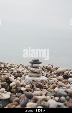 Steinturm am Kiesstrand in der Nähe von ruhigem Wasser Stockfoto