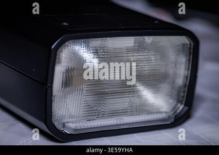 Makroaufnahme eines Blitzkopfes mit Blitzlicht und strukturiertem Fresnel-Objektiv und schwarzem Elektronikgehäuse Stockfoto