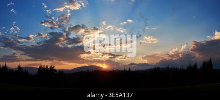 Ruhiger Abendhimmel mit blauen und weichen rosa Wolken bei Sonnenuntergang. Der Horizont leuchtet sanft und wirft Licht über Silhouetten von Kiefern und sanften Hügeln, wodurch eine friedliche und weitläufige Landschaft entsteht. Stockfoto