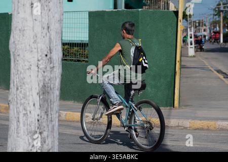 Ein junger Mann auf einem Fahrrad durch eine der Straßen von Ciego de Avila in Kuba Stockfoto