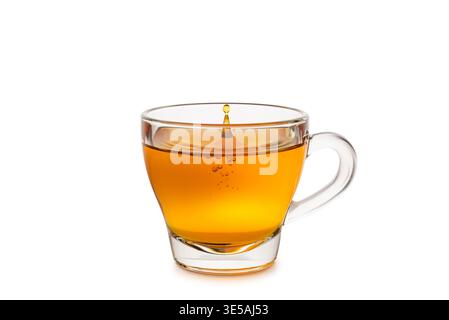 Glasbecher Tee mit tropfendem Tropfen isoliert auf weißem Hintergrund. Stockfoto