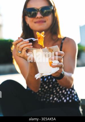 Nahaufnahme einer jungen Reisenden, die draußen Straßenessen isst. Stockfoto