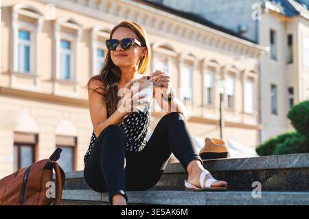 Junge Erwachsene Reisende, die auf städtischen Stufen sitzt und Street Food isst. Stockfoto