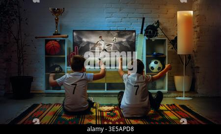 Zwei Jungen sehen sich zu Hause ein Fußballspiel an, um gemeinsam den Tormoment zu feiern. Stockfoto