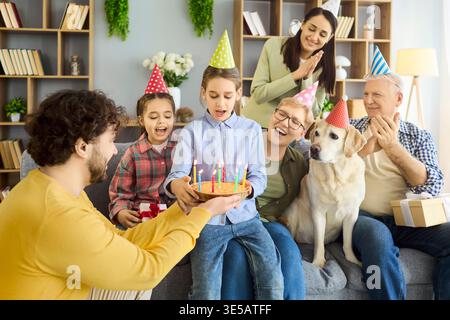 Mehrgenerationengeburtstag zu Hause mit Kuchen, Kerzen, Geschenken und Hund Stockfoto