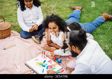 Glückliche indische Familie, die Spaß beim Spielen mit Kindern im Freien im Stadtpark hat - Sommerzeit und Elternschaftskonzept - Hauptfokus auf das Gesicht der Mutter Stockfoto