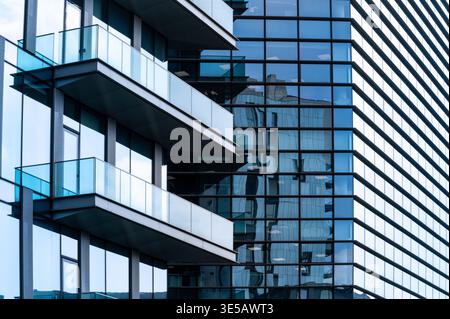 Modernes Architekturgebäude mit Glasfassaden und Balkonen, die das Stadtbild widerspiegeln Stockfoto