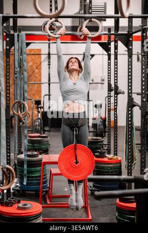 Frau, die eine Hängeübung mit einer Hantelplatte in einem Fitnessstudio durchführt Stockfoto