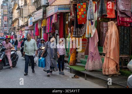 Menschen, die an farbenfrohen Bekleidungsgeschäften in Jaipur, Indien, vorbeilaufen Stockfoto