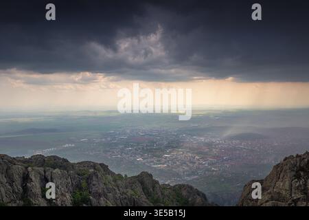 Dramatische Sturmwolken über Sliven City und Tal von den Berghängen von Karandila, Panoramablick aus der Luft Stockfoto