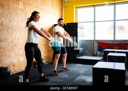 Zwei Personen, die mit Kettlebells trainieren, trainieren in einem Indoor Gym Stockfoto