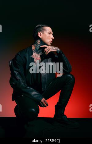 Ein stilvoller junger Mann mit Tattoos posiert dramatisch gegen leuchtende Farben. Stockfoto