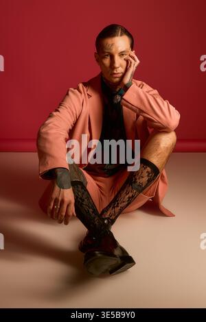 Der trendige junge Mann posiert vor einem leuchtend rosa Hintergrund. Stockfoto
