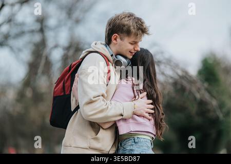 Teenager-Paar umarmt sich draußen mit Rucksack und Kopfhörern und zeigt liebevolle Freundschaft Stockfoto