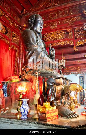 Eine große Buddha-Statue befindet sich in einem Tempel in Ho-Chi-Minh-Stadt. Die Statue ist mit Darbietungen und Dekorationen umgeben, die kulturelle Praktiken zeigen. Stockfoto