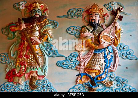 Zwei geschnitzte Figuren vietnamesischer Götter stehen an der Wand in Ho-Chi-Minh-Stadt. Sie zeigen kulturelle Kunst und Tradition in der Stadt. Stockfoto