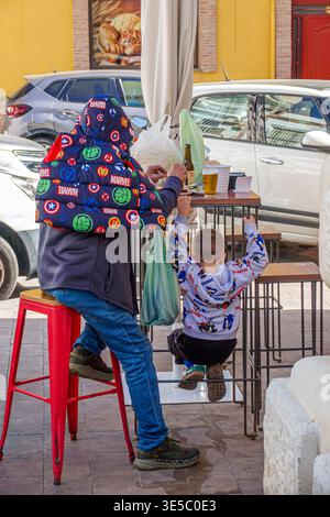 Malaga Spanien, Andalusien, El Molinillo Capuchinos, Mercado Municipal de Salamanca, Lebensmittelmarkt in der Nachbarschaft, Mann Erwachsene männlich und Kind Junge essen im Stehen ta Stockfoto