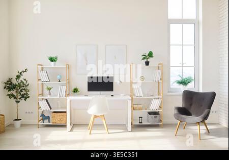 Skandinavischer Heimbüro-Arbeitsplatz mit Schreibtisch, Computerregalen, Pflanzen und Sessel Stockfoto