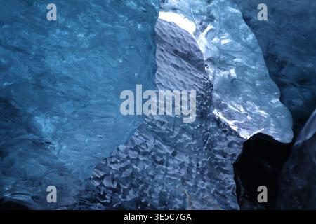 Blaue Eisformationen in einer Gletscherhöhle im isländischen Vatnajökull-Nationalpark schaffen abstrakte Texturen und eine gefrorene Wasserfallszene. Stockfoto