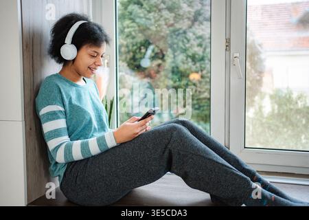 Junge Frau, die Musik über Kopfhörer mit dem Smartphone hört Stockfoto