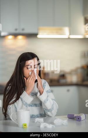 Frau, die die Nase ins Gewebe bläst und sich unwohl und krank fühlt Stockfoto