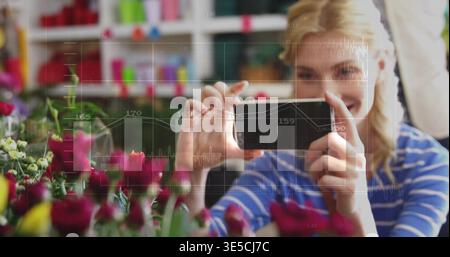 Eine Frau in blau-weiß gestreiftem Oberteil, die im Blumenladen das Telefon hält und Rosen zeigt Stockfoto