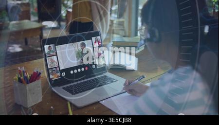 Schreib-Kind mit gestreiftem T-Stück und beobachte Kollegen auf dem Laptop am Schreibtisch, Notebook, Headset Stockfoto