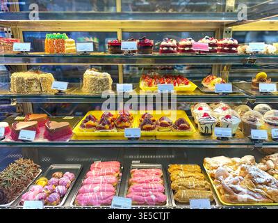 In einer Bäckerei werden verschiedene Gebäckstücke und Desserts serviert, die Kuchen, Torten und bunte Süßigkeiten in verschiedenen Formen und Größen bieten Stockfoto
