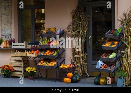 Ein farbenfroher Außenstand mit mehreren Holzkisten und Körben, gefüllt mit einer Vielzahl von Obst und Gemüse, einschließlich Kürbissen, Kürbis, A Stockfoto