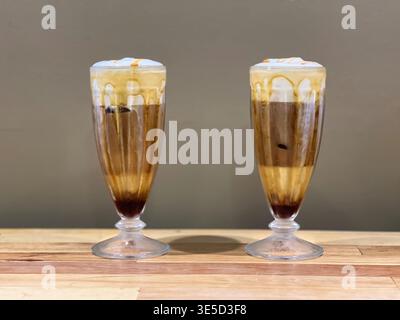 Zwei Iced Caramel Macchiatos auf einem Holztisch Stockfoto