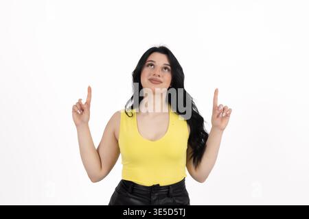 Eine junge Frau, die aufblickt und mit den Fingern zeigt Stockfoto