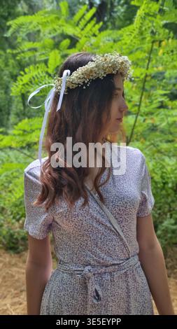 Junge Frau mit Blumenkranz, die im Wald steht Stockfoto