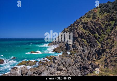 Blick aus einem hohen Winkel auf türkisfarbene Meereswellen, die gegen zerklüftete Küstenfelsen krachen, wilde Meereslandschaft Stockfoto