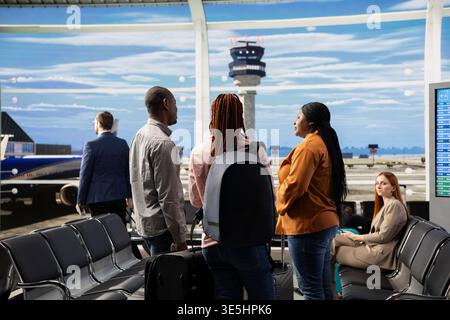 Glückliche Familienpassagiere in guter Laune, die zusammen im geschäftigen Flughafenterminal reisen, mit Taschen und Rucksäcken. Eltern und Teenager-Tochter stehen mit Rucksäcken bereit zum Tor. Stockfoto