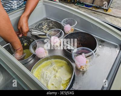 Eine Nahaufnahme der Hände eines Straßenverkäufers, der „es Putar Jadul“ zubereitete, ein traditionelles indonesisches Eis. Die Ebene des Anbieters wird angezeigt Stockfoto