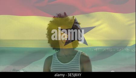 Lachender Mann in gestreiftem Tanktop am Wasserrand, mit Ghana-Flagge und schwarzem Stern Stockfoto