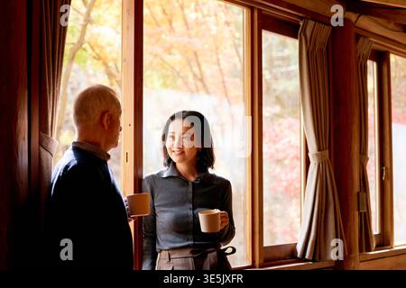 Glückliches japanisches Seniorenpaar, das sich bei Kaffee unterhält Stockfoto