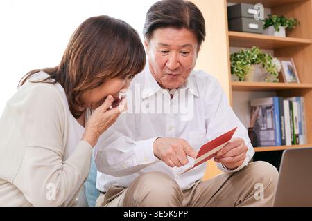 Ein japanisches Seniorenpaar überrascht über die Investitions- und Rentenpläne zu Hause Stockfoto