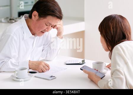 Japanisches Seniorenpaar diskutiert zu Hause finanzielle Sorgen und Zukunftspläne Stockfoto