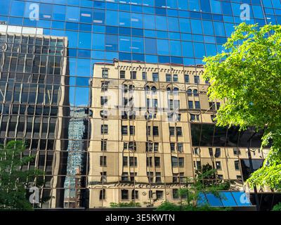 Ein modernes, verglastes Gebäude, das ein älteres, verziertes Gebäude auf der anderen Straßenseite in Montreal, Quebec, Kanada reflektiert Stockfoto
