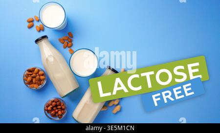 Laktosefreie Produkte auf blauer Oberfläche mit Nüssen und Milchgläsern in der Nähe von Glasflaschen Stockfoto