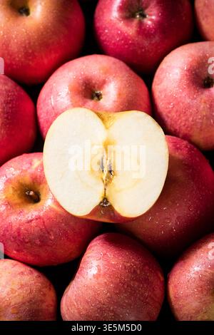 Rote Äpfel mit Wassertröpfchen, mit geschnittenem Apfel, der seinen Kern offenbart Stockfoto