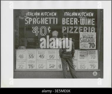 Anthony Angel (1906–1967) – Italian Kitchen Storefront – Mann, der auf die Schaufenster eines italienischen Restaurants in New York City blickt. Auf dem Fenster sind Preise für verschiedene Gerichte und durch das Fenster hat man einen Blick auf den Koch - 1956 Stockfoto